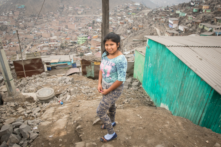Une jeune fille devant un bidonville.
