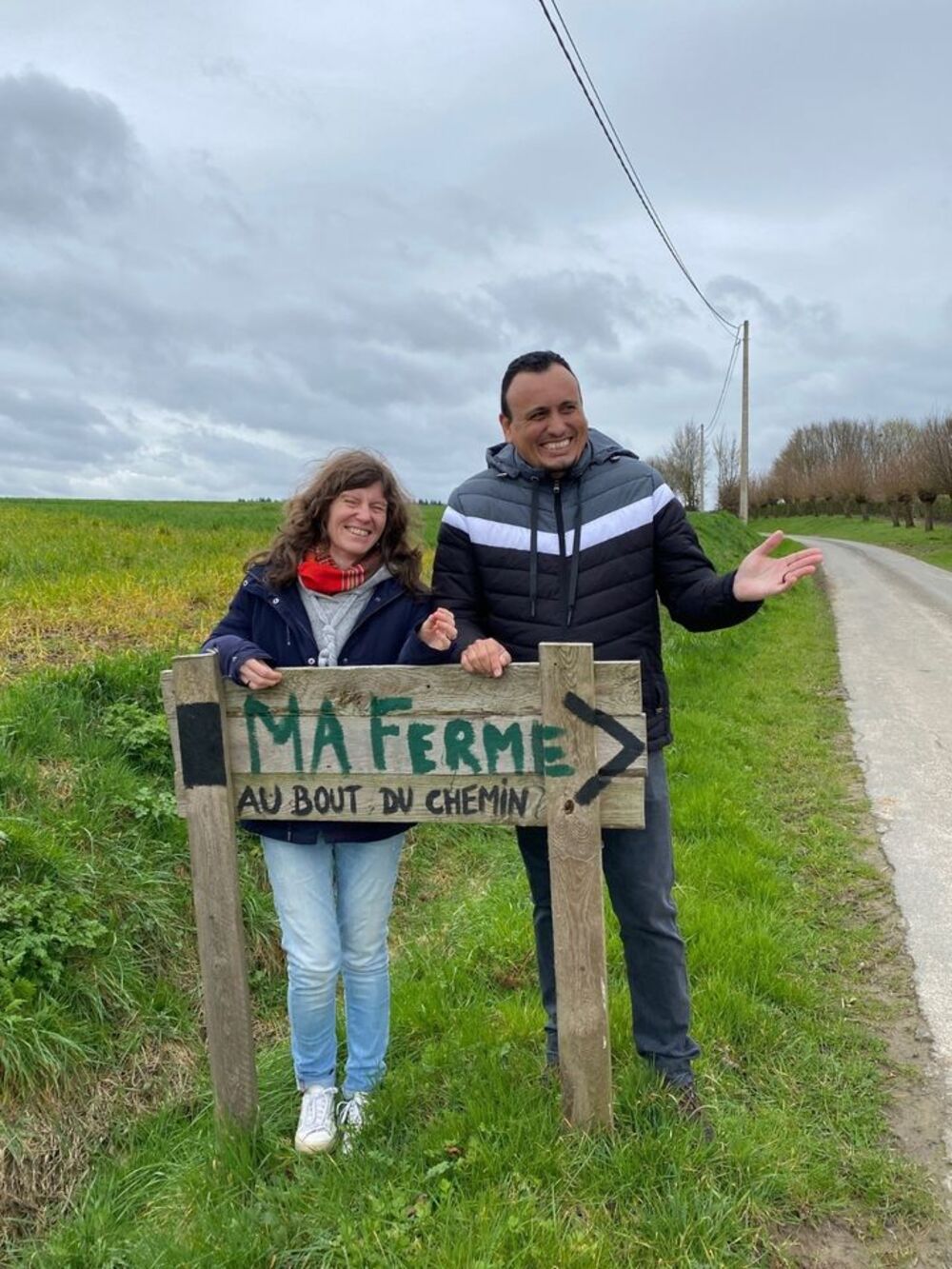 Saulo Reis et Dolores Fourneau posent derrière un panneau "Ma Ferme, au bout du chemin"