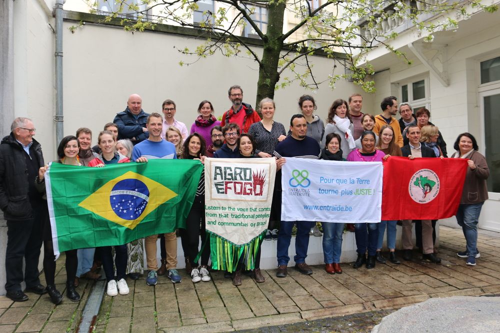 photo de groupe, le premier rang tien des drapeaux d'Entraide et Fraternité, Agro et Fogo, du Mouvement des Paysans Ruraux Sans Terres et du Brésil