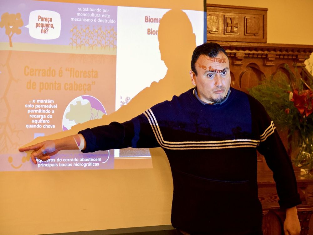 Saulo Reis devant une projection de présentation. Il point un détail sur l'écran.