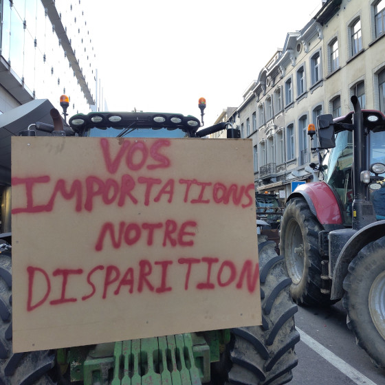 Un tracteur avec une pancarte : "Vos importations notre disparition"