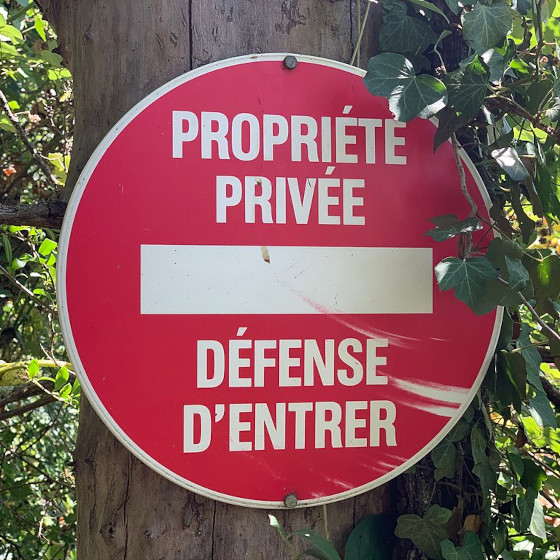 Un panneau cloué sur un arbre : Propreté privée, défense d'entrer