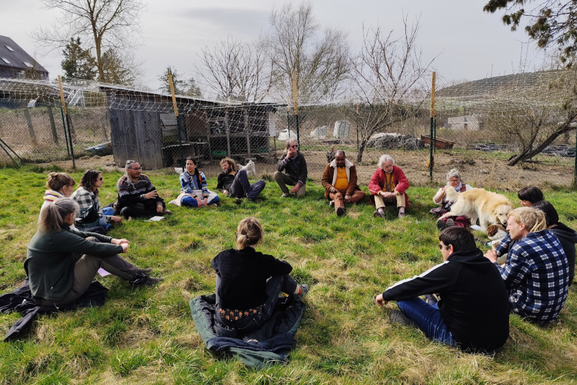 Une vingtaine de personne assise en cercle sur l'herbe