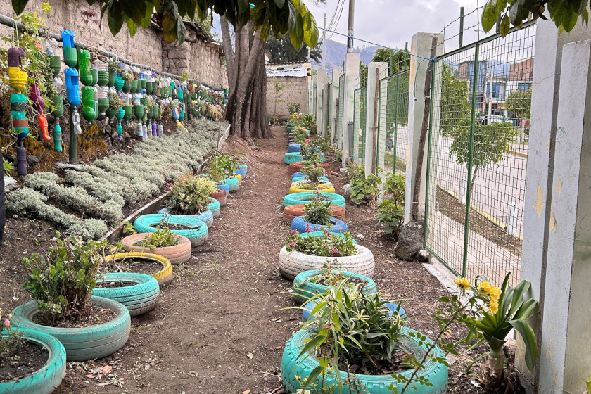 Un chemin bordé de plantations. Des pneus de voiture peints de couleurs vives et des bouteilles en plastique découpées servent de pots de fleurs.
