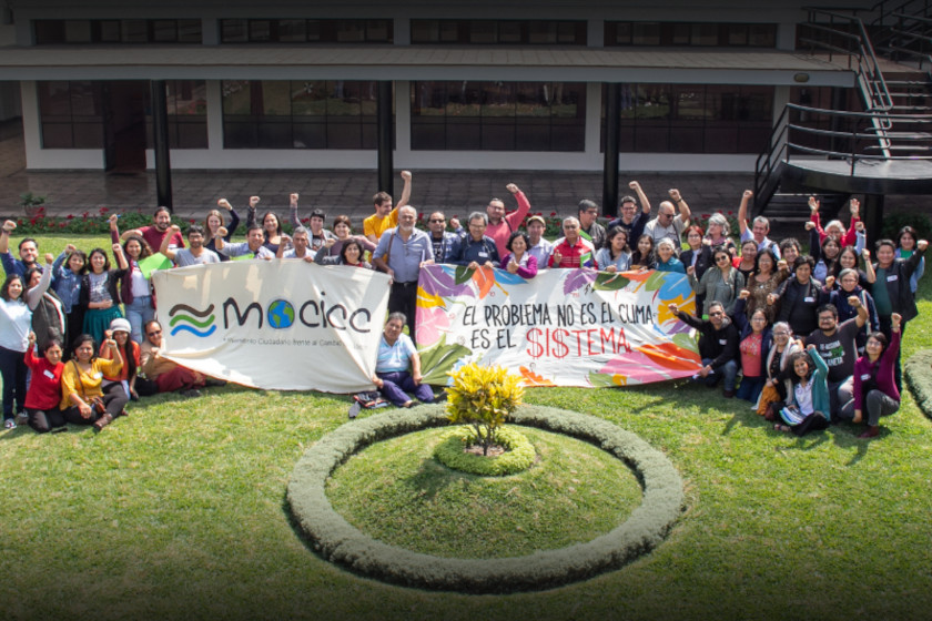 Photo de groupe d'une 50aine de personnes avec deux banderôles : "MOCICC" et "El problema no es el cuma es el $i$tema"