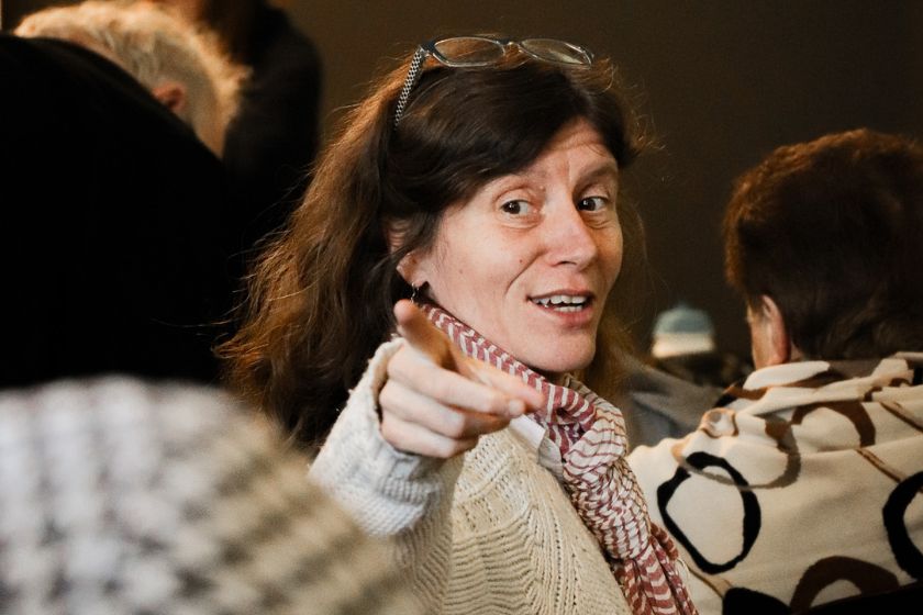Une femme assise pointant à la caméra avec un sourire