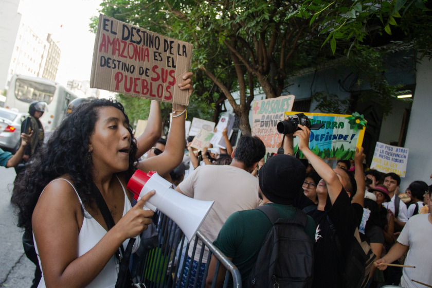 Une manifestation, des gens portent des pancartes, en avant plan une personne avec un mégaphone