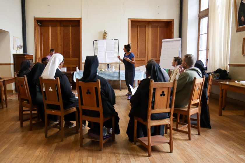 Une personne parle devant un groupe assise en cercle.