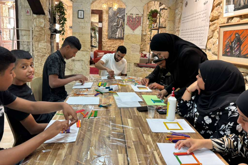 Des jeunes gens autour d'une grande table, occupés à dessiner sur des feuilles blanches
