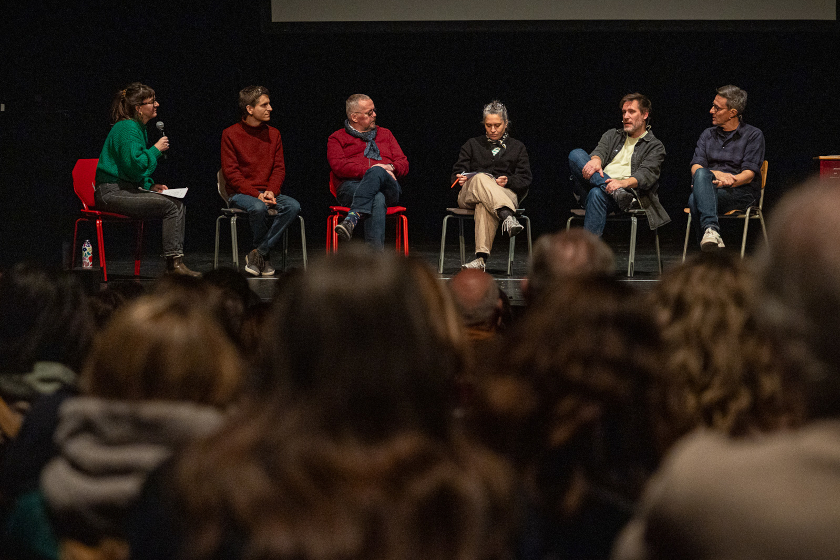 Panel de six intervenants assis sur scène devant un public lors d’un débat.